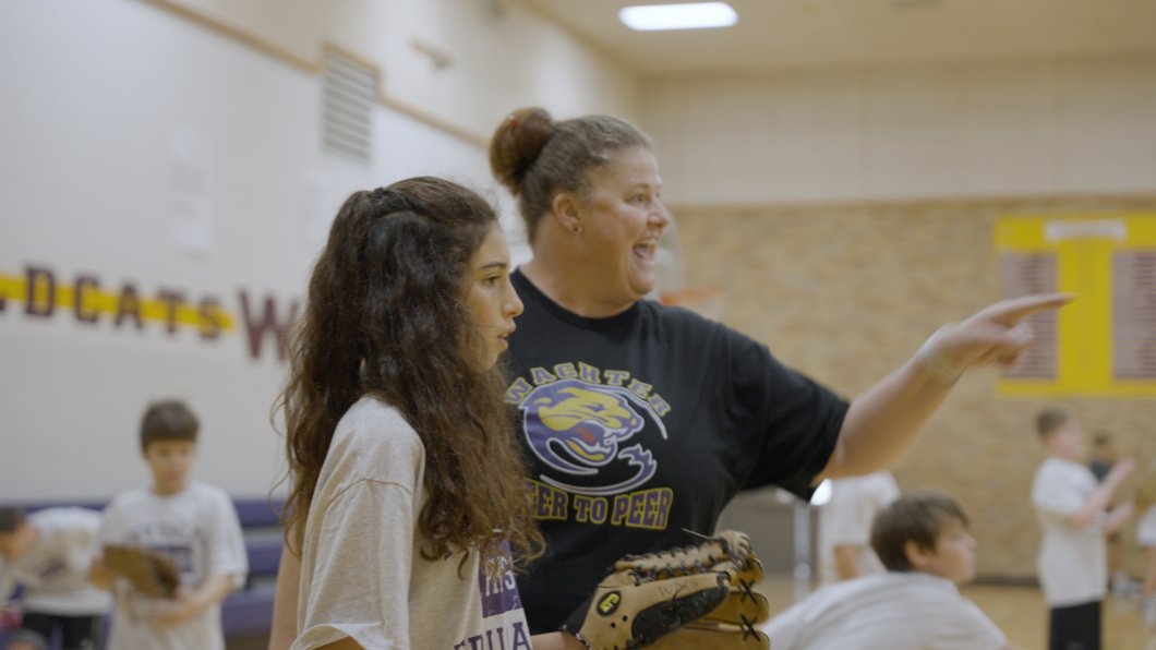 Peterson enthusiastically pointing while assisting a student in phy ed class;