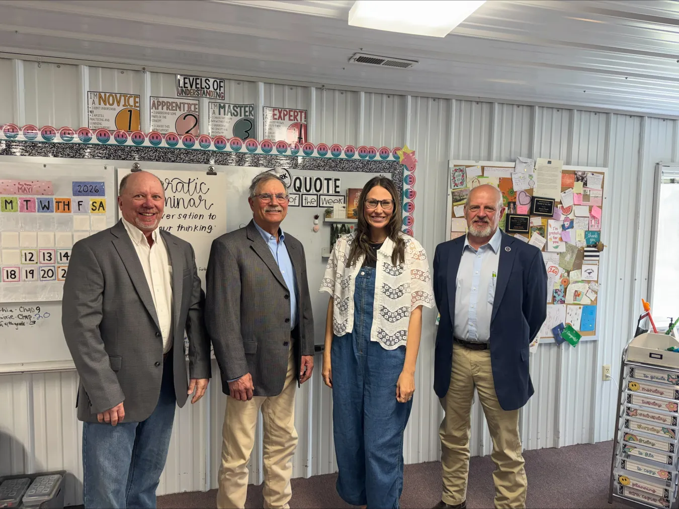Rep. Dave Rustebakke, Sen. Randy Lemm and Rep. Mike Beltz stand with 2026 North Dakota Teacher of the Year Frannie Tunseth in her classroom at May-Port CG Middle School during a visit to observe teaching and learning.