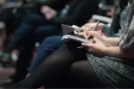 group of people sitting in crowd taking notes