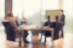 blurry image of group sitting at conference table