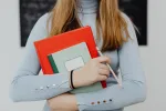 woman staking holding books against her chest