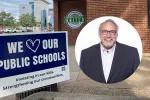 Sign that reads "We Love Our Public Schools" in front of office building with North Dakota United logo on the wall, along with circular photo of man in glasses, smiling and wearing a black suit with white collared shirt.