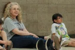 2027 North Dakota United Education Support Professional of the Year Dawn Ressler sits on a gym floor with elementary students during a physical therapy activity at Mandan Public Schools. Ressler smiles as she engages with the children during a playful movement exercise.