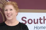 Portrait of Laurie Holcomb, a special education paraprofessional at South Middle School in Grand Forks and a finalist for North Dakota United's 2027 Education Support Professional of the Year. She smiles while standing in front of a school sign.