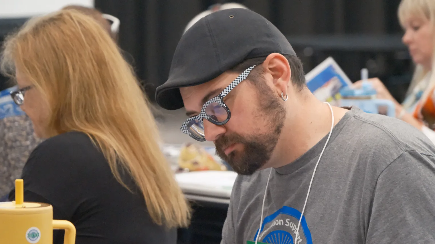 Man in gray shirt with Bismarck Education Association logo on it, looking down.