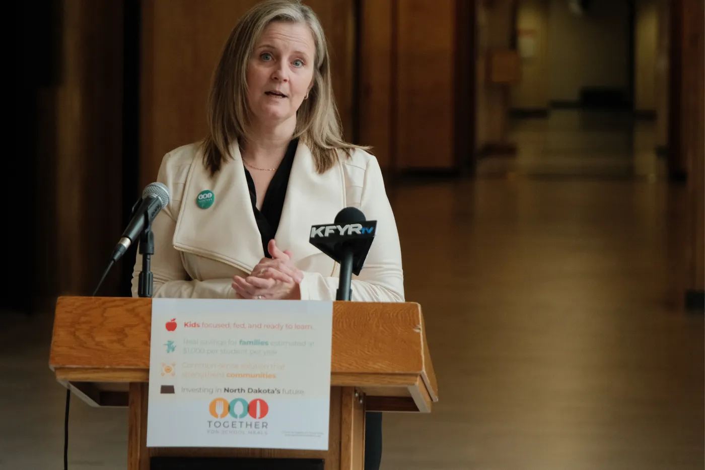 A speaker stands at a podium with microphones during the school meals initiative press conference.