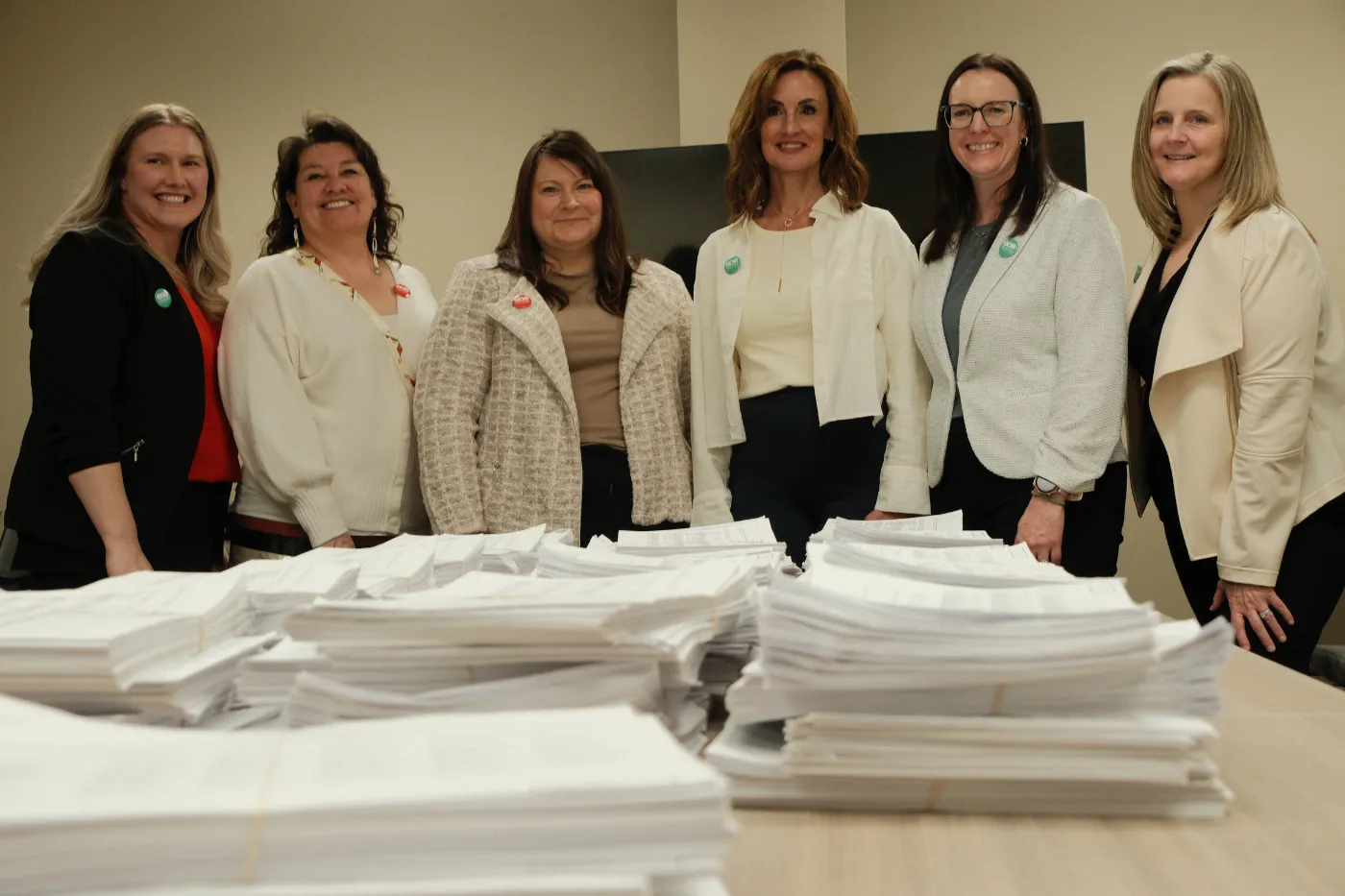 Coalition members pose behind stacks of completed petition signatures.