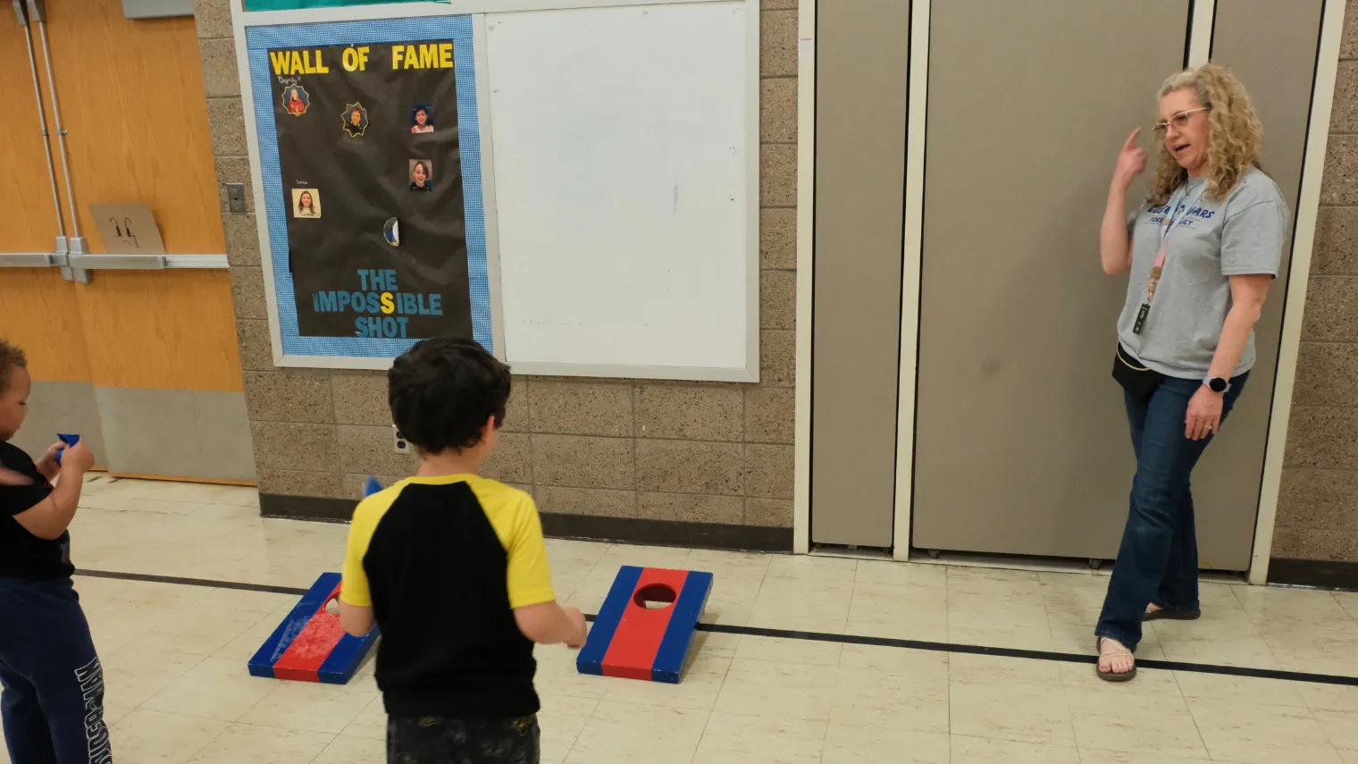 Dawn Ressler gives instructions to elementary students as they prepare to take turns in a beanbag toss activity designed to build coordination and motor skills.