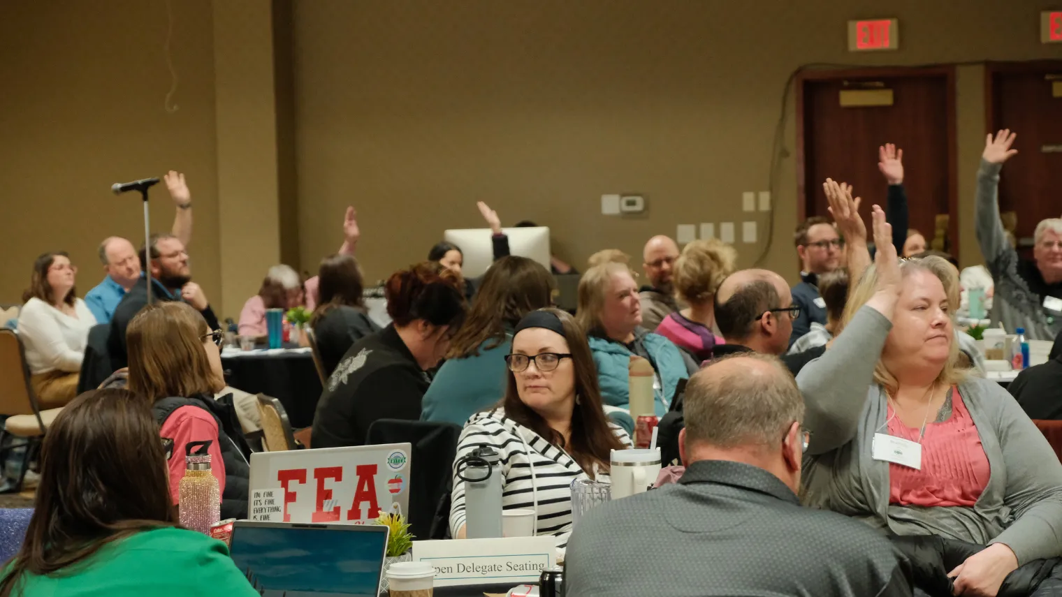 Delegates raise their hands during discussion at the 2026 North Dakota United Delegate Assembly.