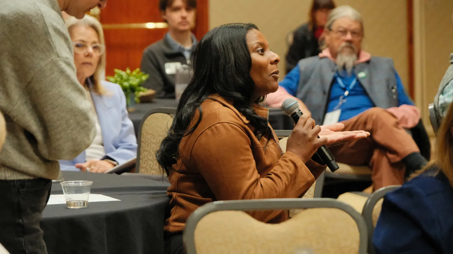Tiffany Williams-Rice, a Bismarck Education Association delegate, speaks into a handheld microphone while participating in discussion during the 2026 North Dakota United Delegate Assembly.