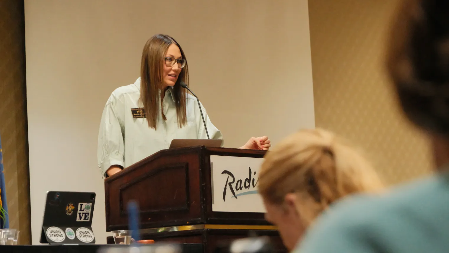 2026 North Dakota Teacher of the Year Frannie Tunseth speaks from the podium during the North Dakota United Delegate Assembly.