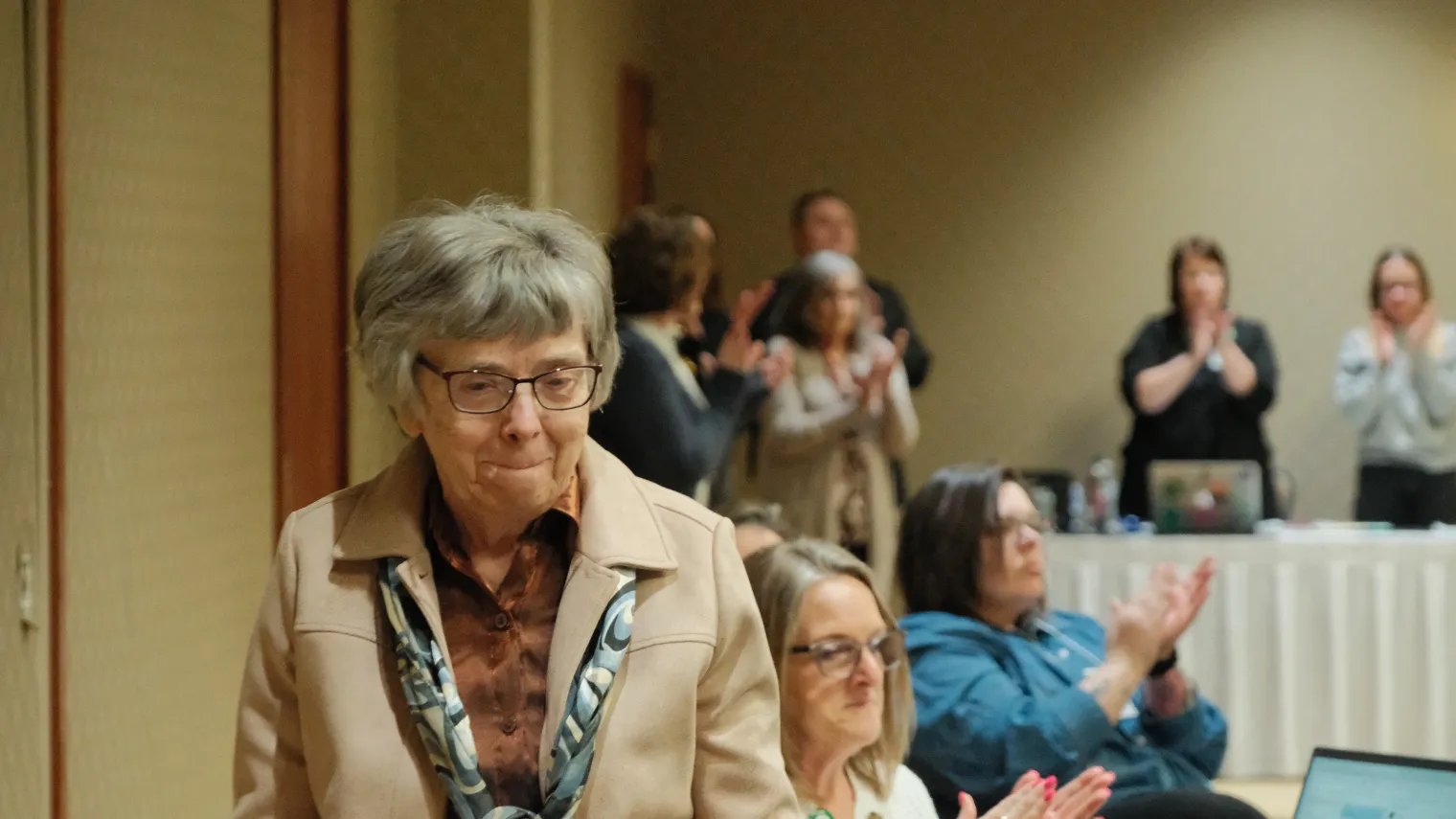 Marie Snavely, a recipient of the North Dakota United Foundation's Friend of the Foundation award, walks to the front of the room as delegates applaud.