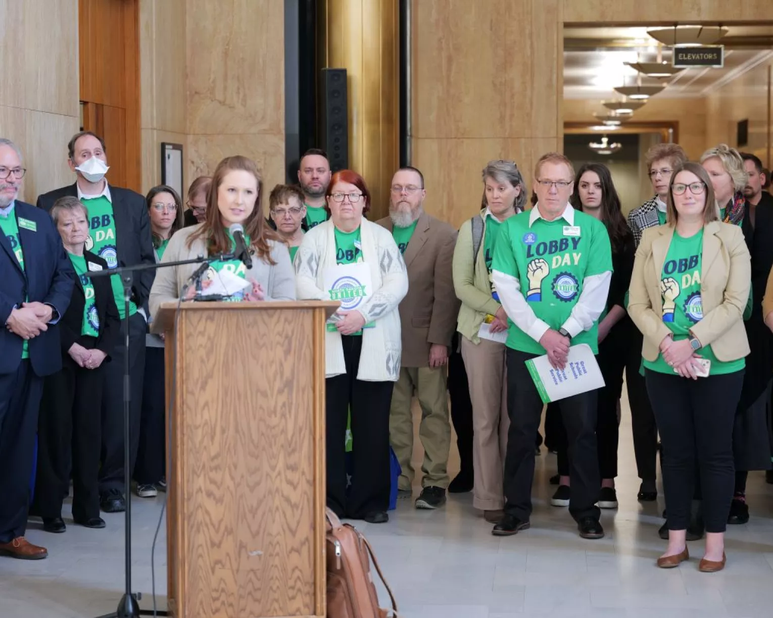 image of a crowd with a woman standing at a podium speaking