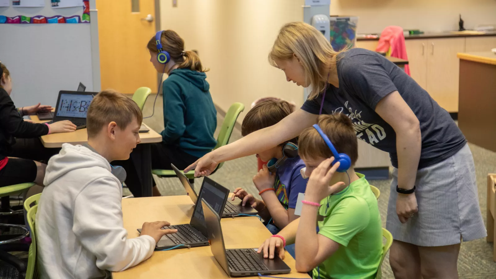 Woman working with a group of students on their computers