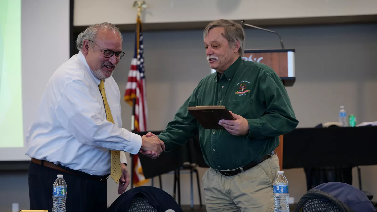 two men shaking hands after winning an award