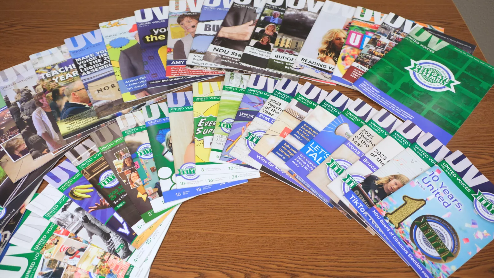 past issues of the united voices magazine spread on a table