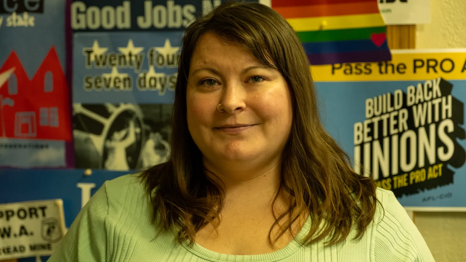 Woman stands in front of union posters in labor hall.