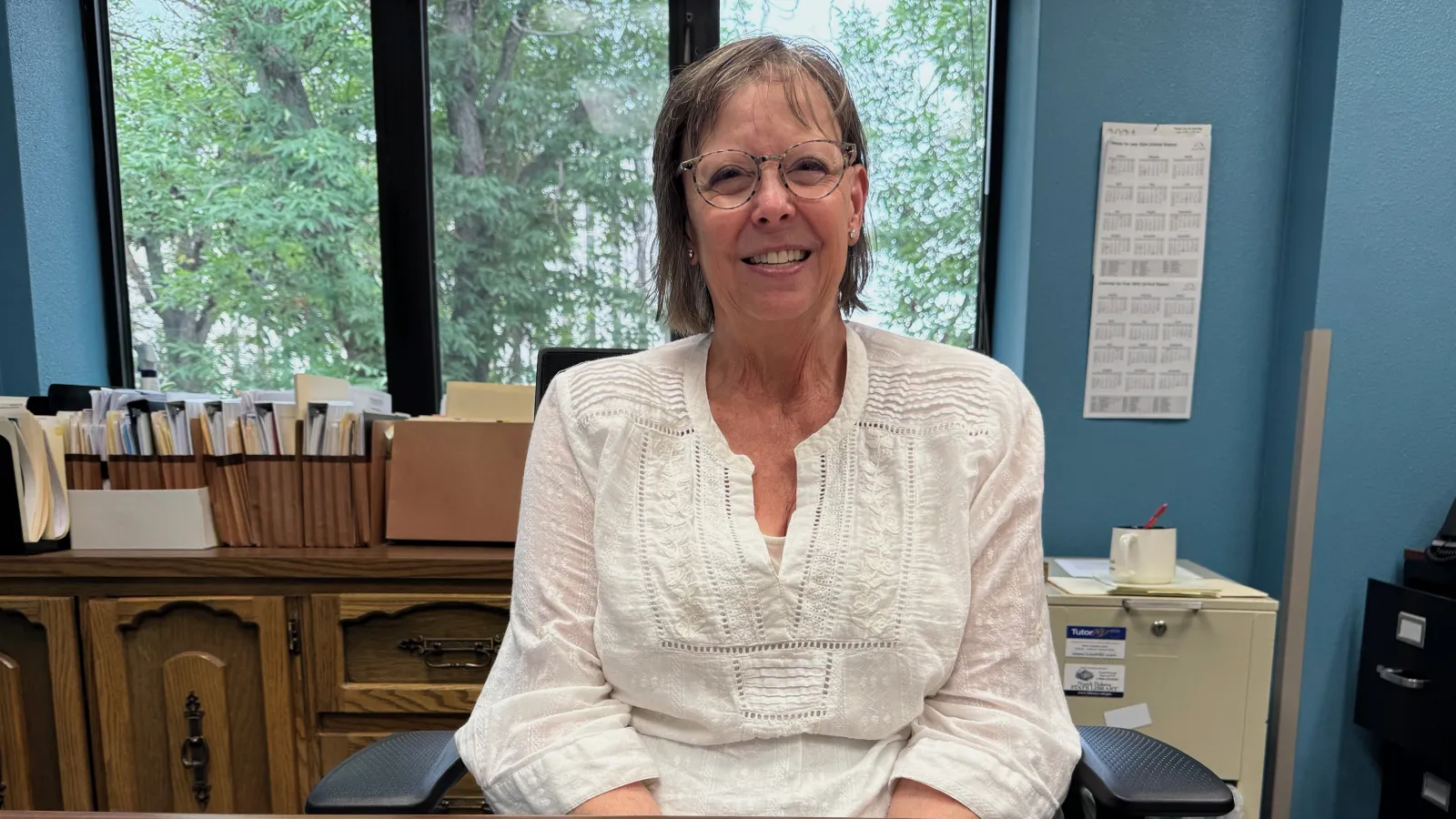 Woman smiling in front of office window.