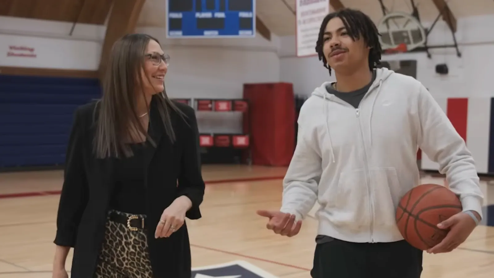 2026 North Dakota Teacher of the Year Frannie Tunseth smiles while walking and talking with May-Port CG Public Schools student Noah Djibonan in the school gym during filming for a North Dakotans for Public Schools advertisement.