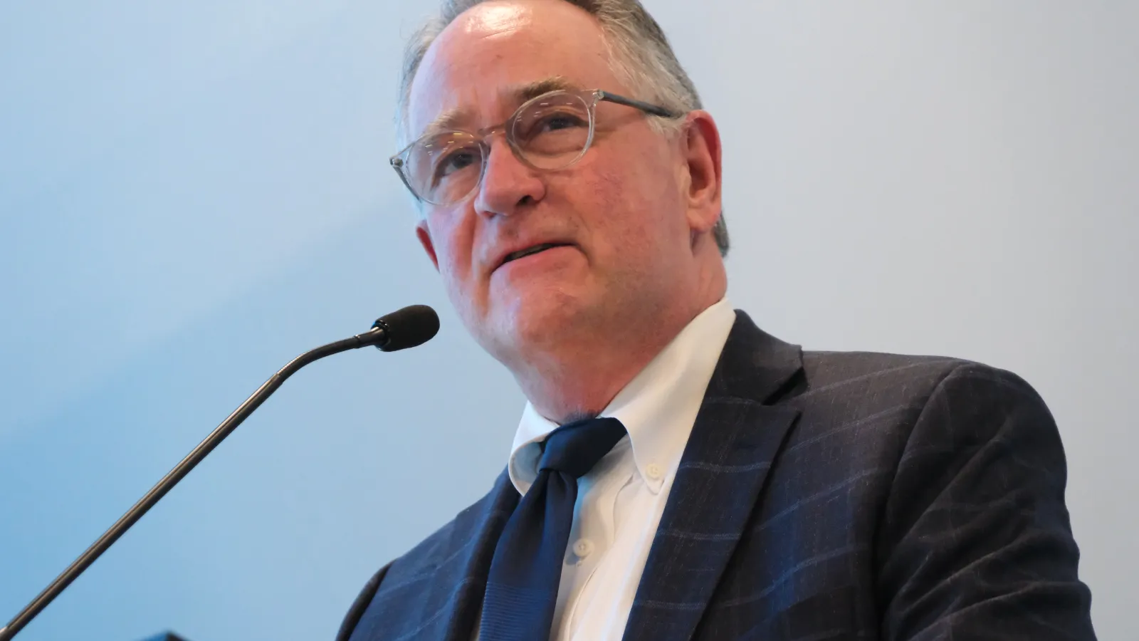 Long-time NDEA/NDU legal counsel Mike Geiermann speaks into a microphone at the 2024 NDU Delegate Assembly in Bismarck.