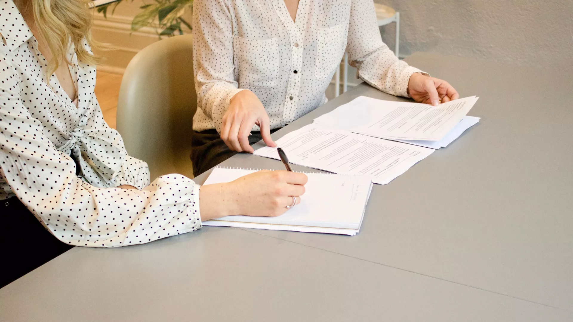 two women sitting at table reviewing documents