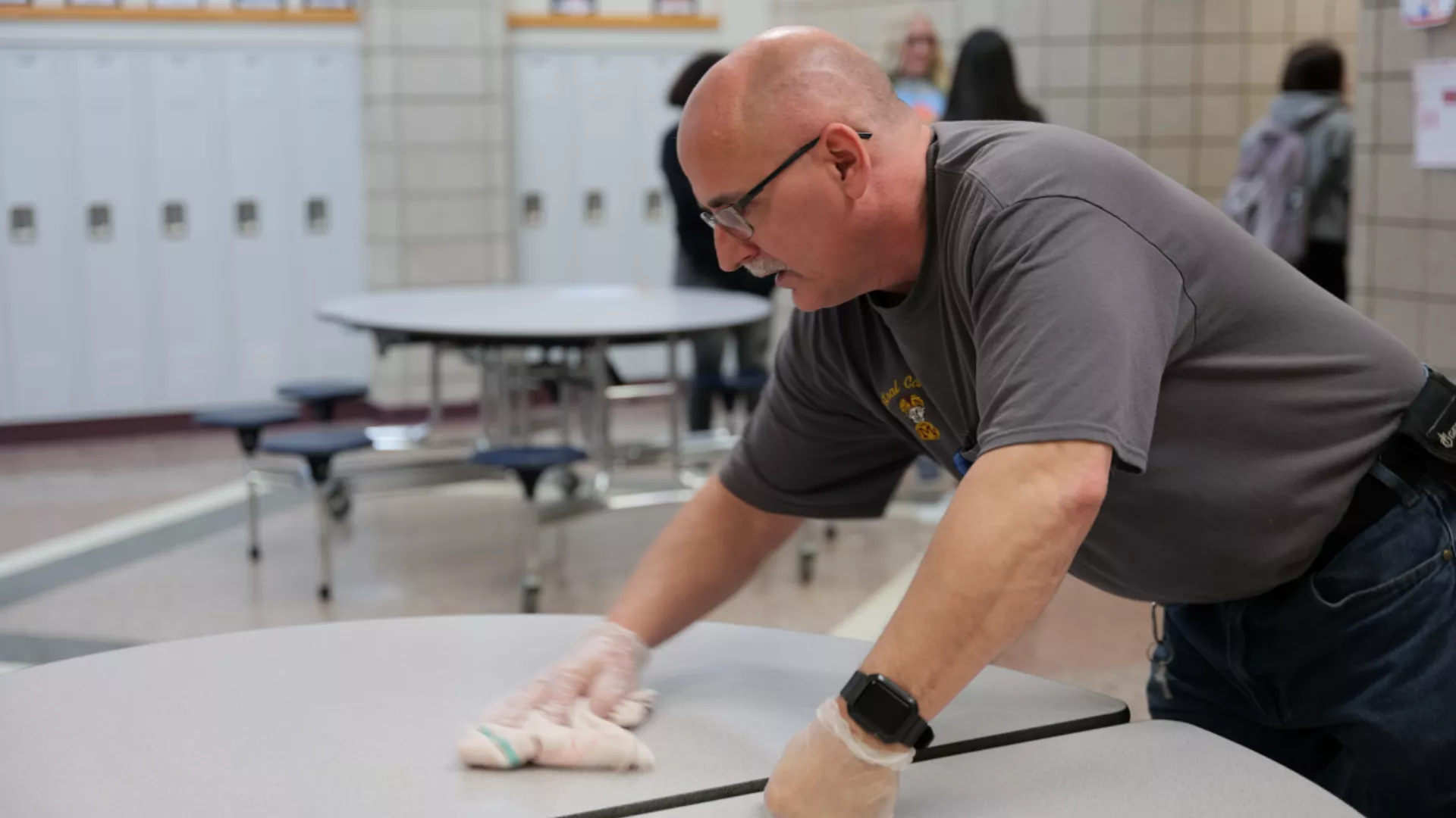 school custodian Bruce Schonberger wipes table