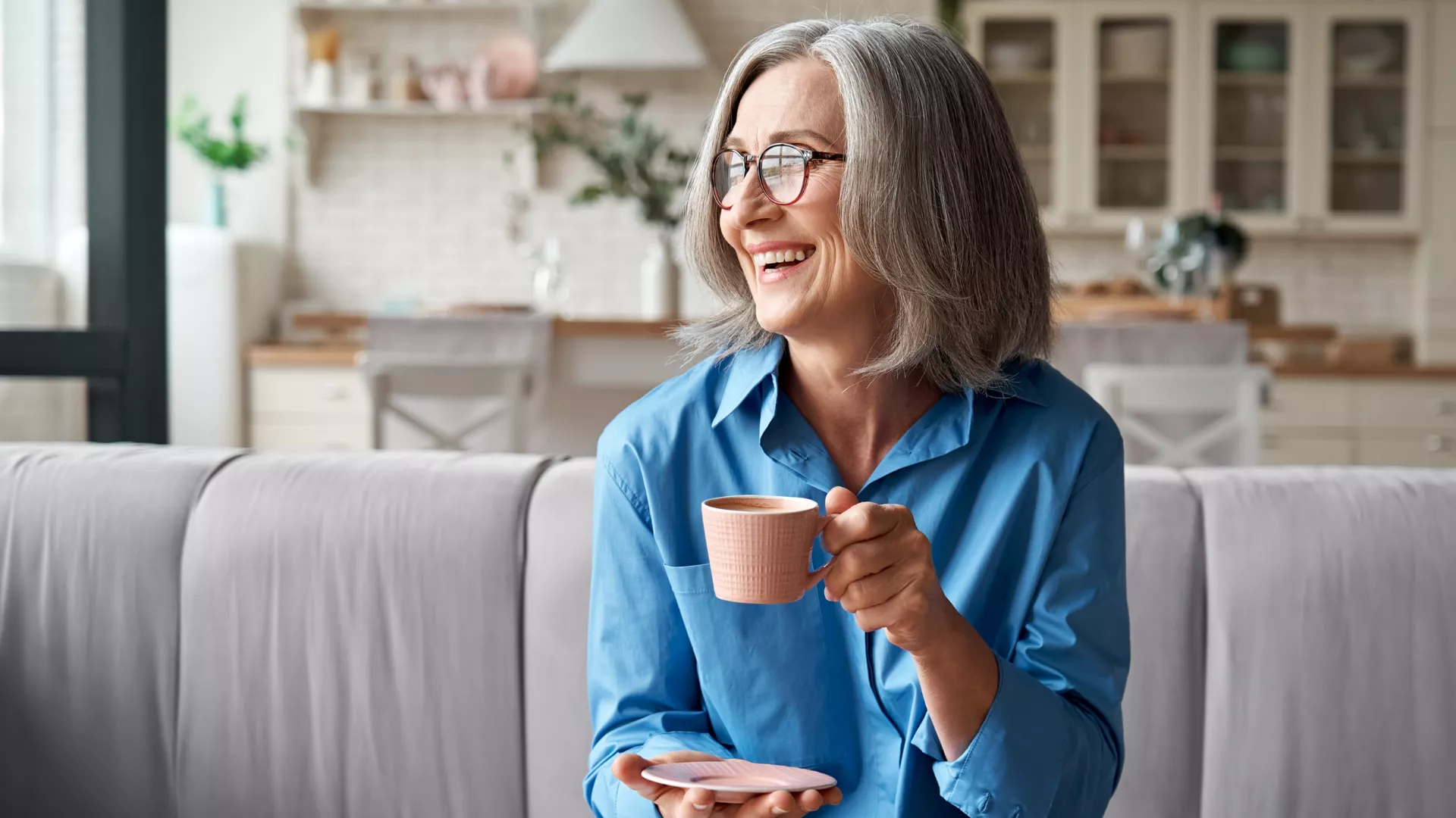older woman sitting on couch drinking coffee