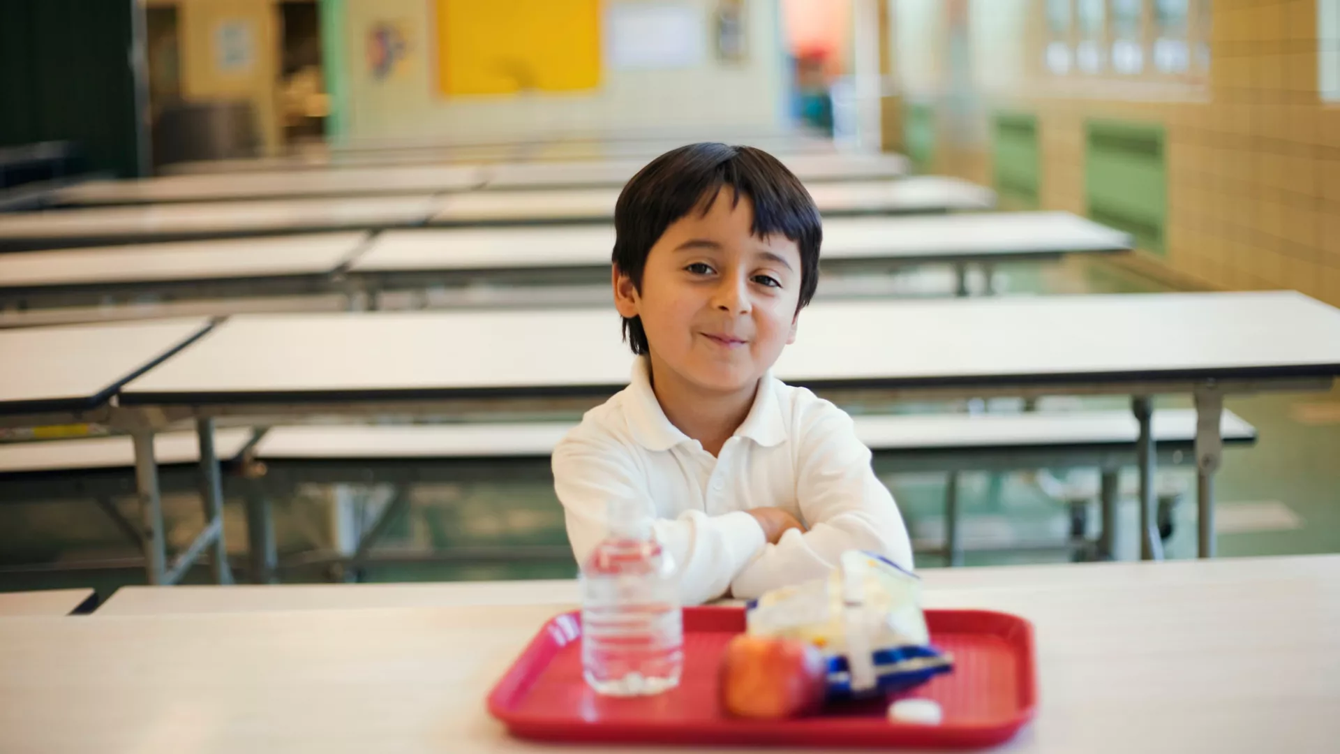 child sitting at school lunch table with red tray