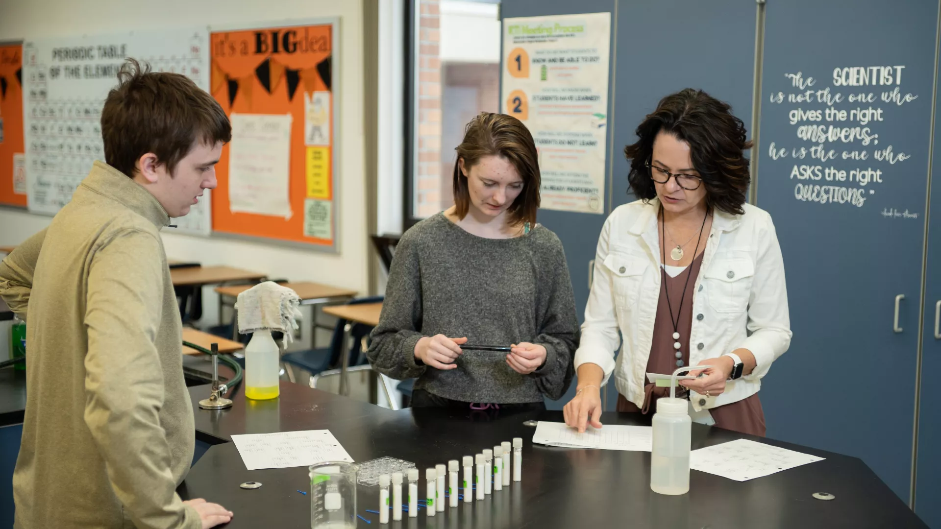 science teacher doing an experiment with two students