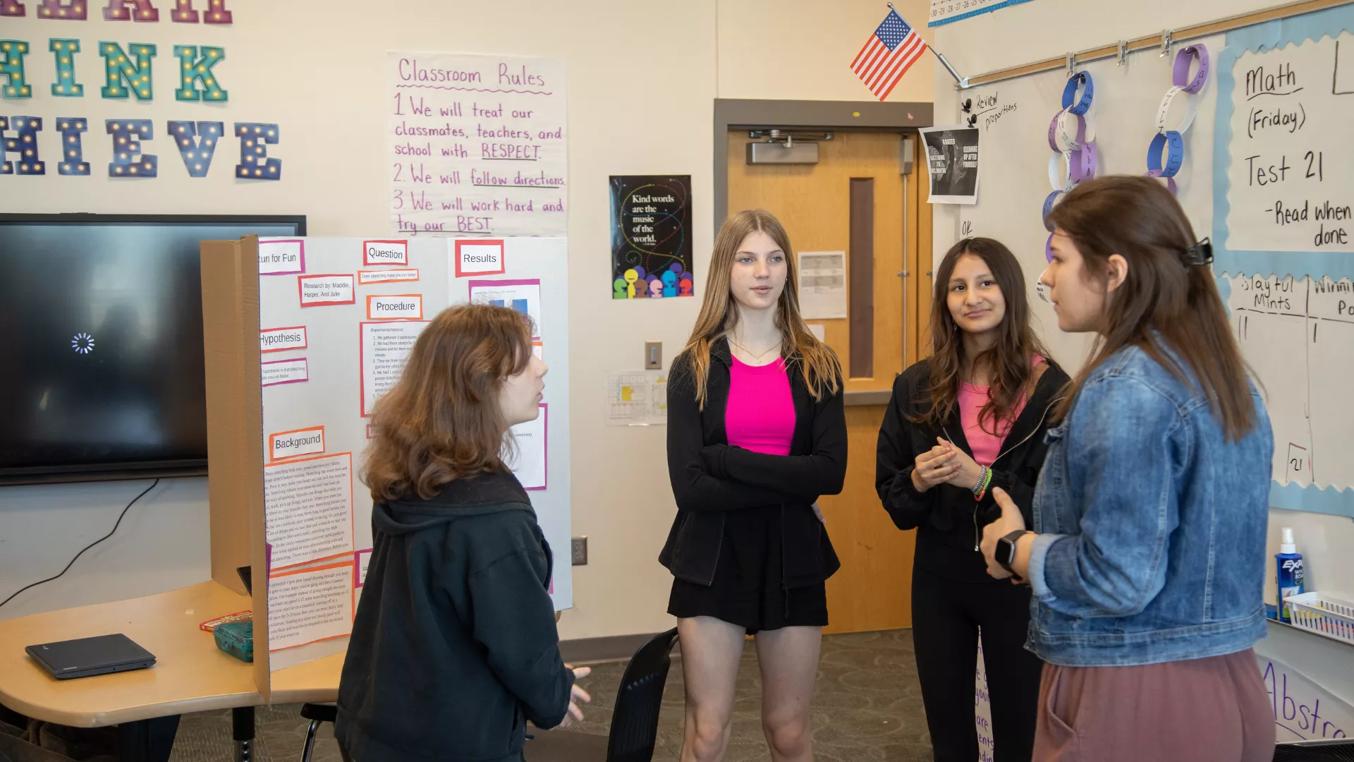 female teacher standing talking to students at science fair