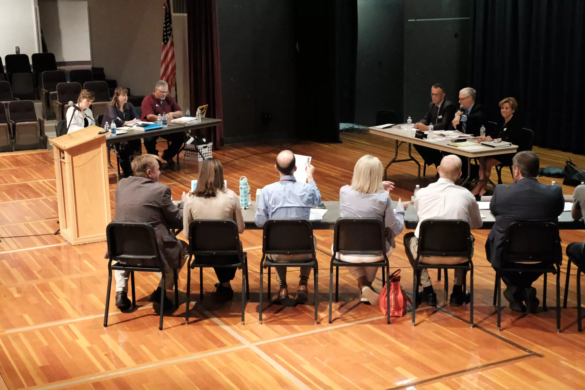 Negotiators from Minot Education Association and school board sit at tables in gymnasium as Fact Finding Commission's impasse hearing in 2018.