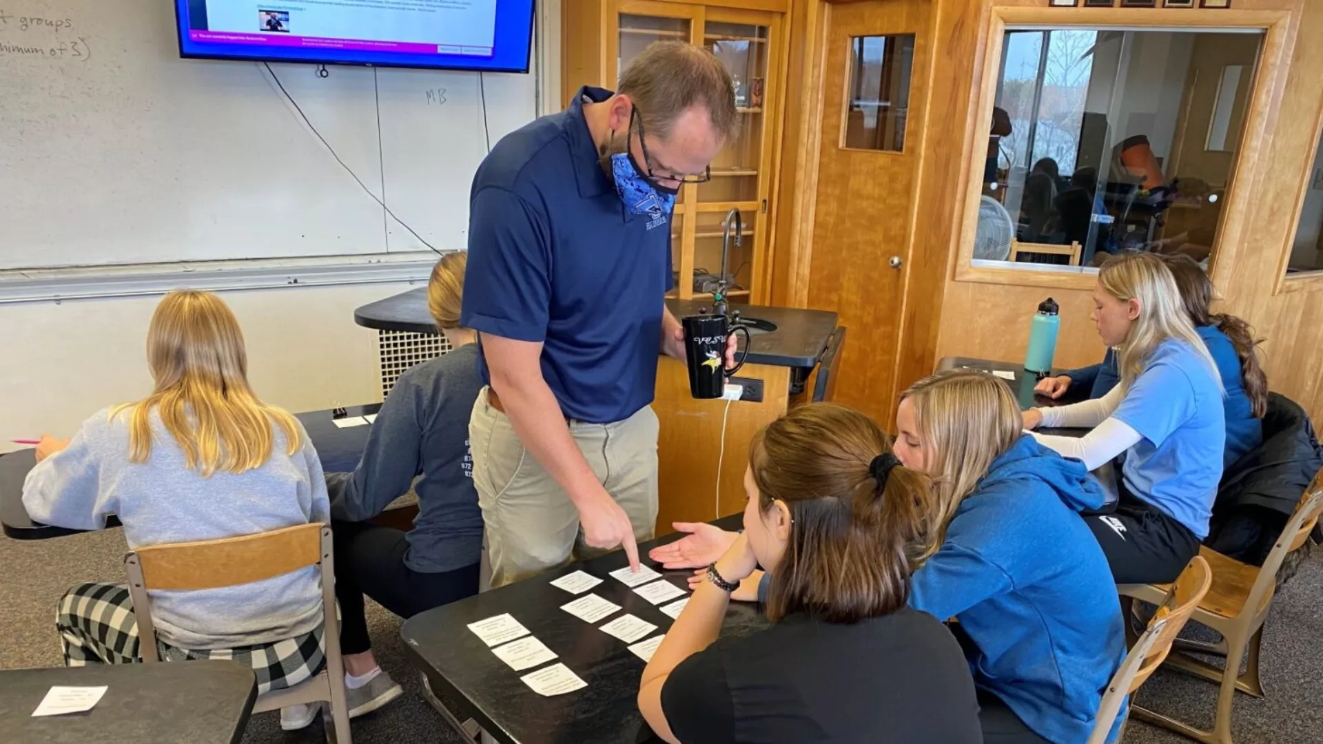 teacher standing over student's desk helping them
