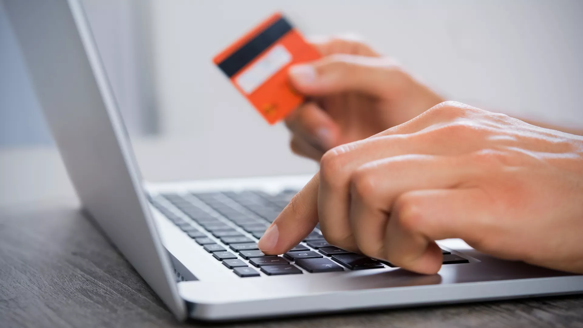 closeup of hands typing on a computer holding a credit card