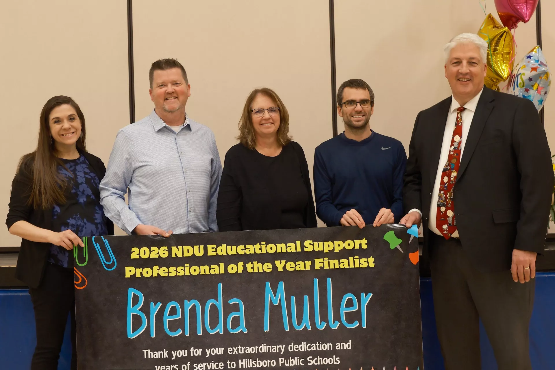Group of five people standing behind a sign congratulating Brenda Muller for being named a finalist for Education Support Professional of the Year.