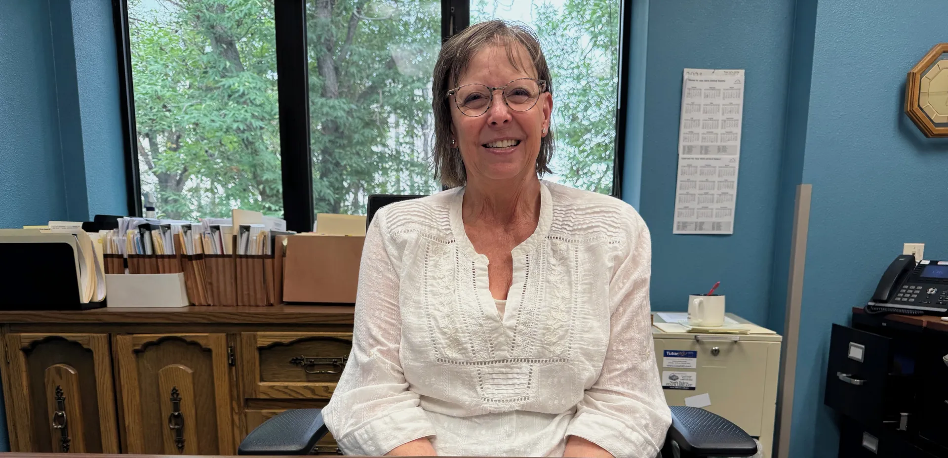 Woman smiling in front of office window.