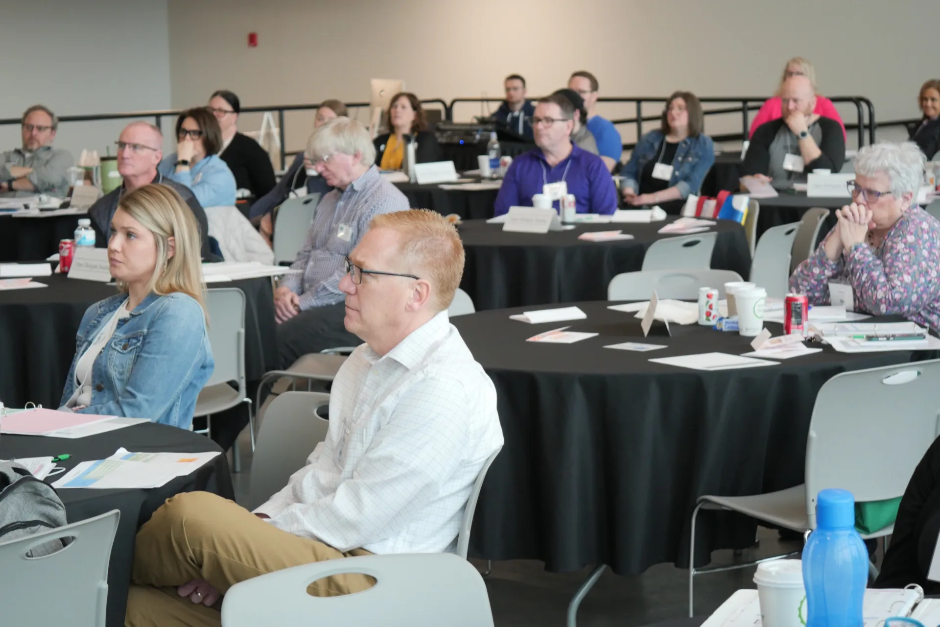 Conference room filled with people, listening to a speaker.
