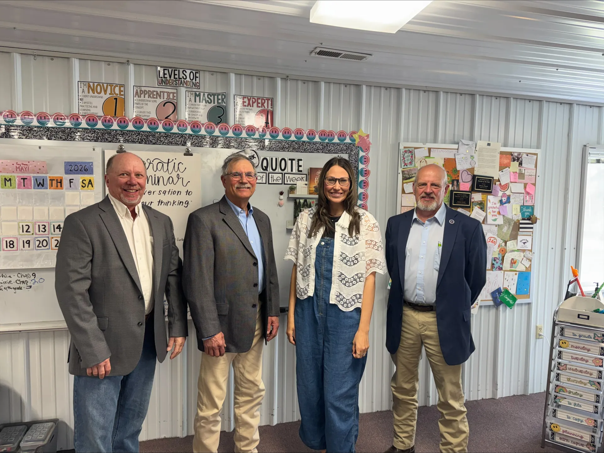 Rep. Dave Rustebakke, Sen. Randy Lemm and Rep. Mike Beltz stand with 2026 North Dakota Teacher of the Year Frannie Tunseth in her classroom at May-Port CG Middle School during a visit to observe teaching and learning.