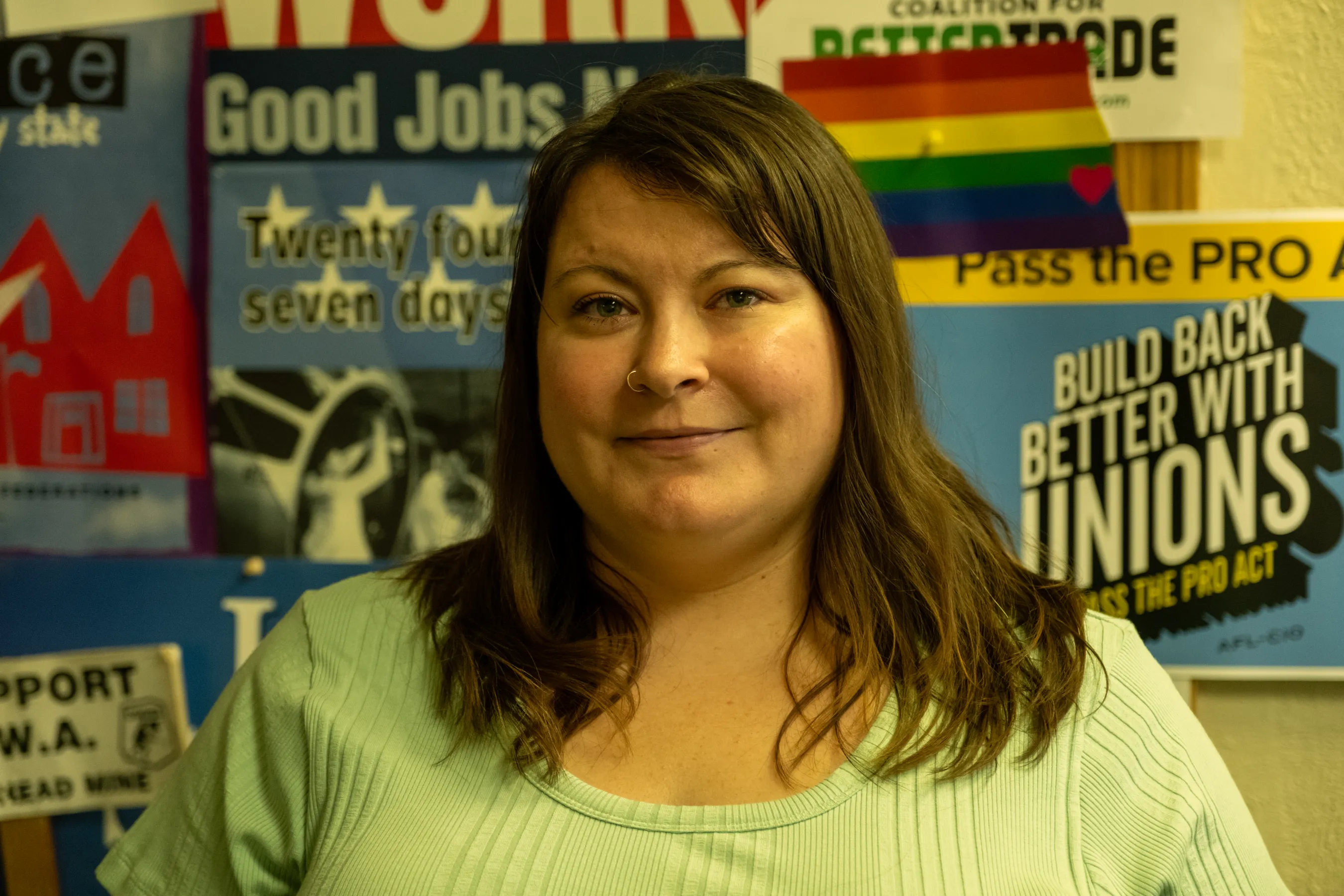 Woman stands in front of union posters in labor hall.