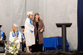young woman in cap and gown accepting award