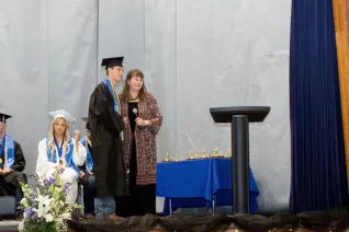young man in cap and gown accepting award