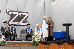 young woman in cap and gown accepting award