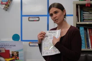 woman standing in classroom pointing at a paper