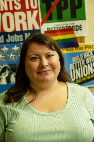 Woman in green shirt standing in front of labor posters.