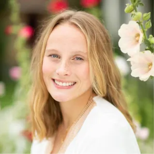 Young woman sitting in field of flowers.