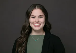 Young woman smiling for camera in front of brown background.