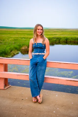 Young woman standing on bridge with river in background.