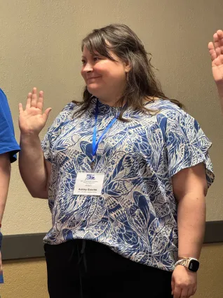 Woman standing with right arm raised as she is sworn in as officer of ND AFL-CIO.