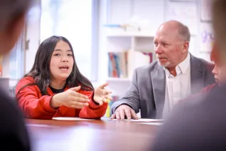 Rep. Dave Rustebakke listens as a student speaks during a classroom visit..