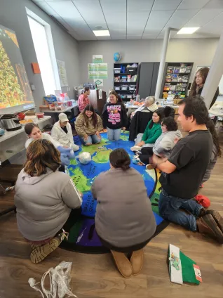 Student members of the United Tribes Technical College Student Education Association gather in a classroom for a holiday-themed team-building activity, sitting in a circle and participating in a group game.