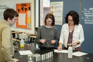 science teacher doing an experiment with two students